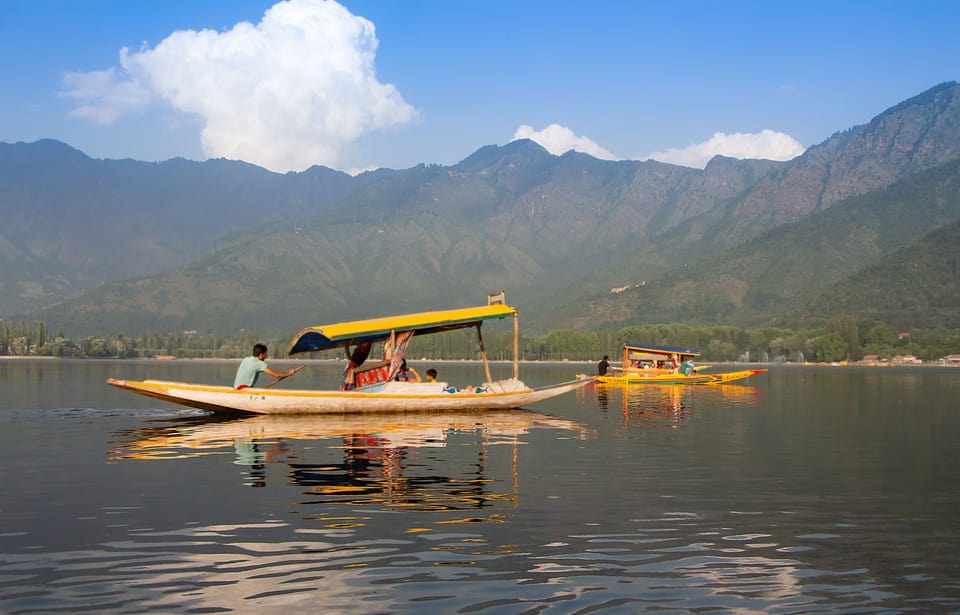 A shikara on Dal Lake in Srinagar, with mountains beyond.
