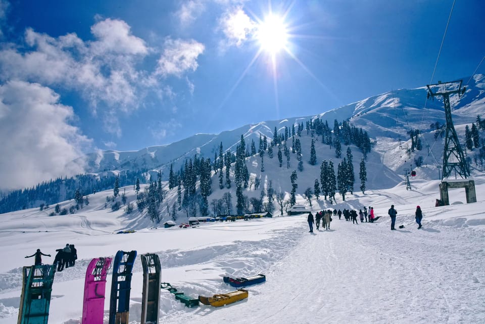 Snow-covered slopes and ski equipment beneath a bright mountain sky in Gulmarg.
