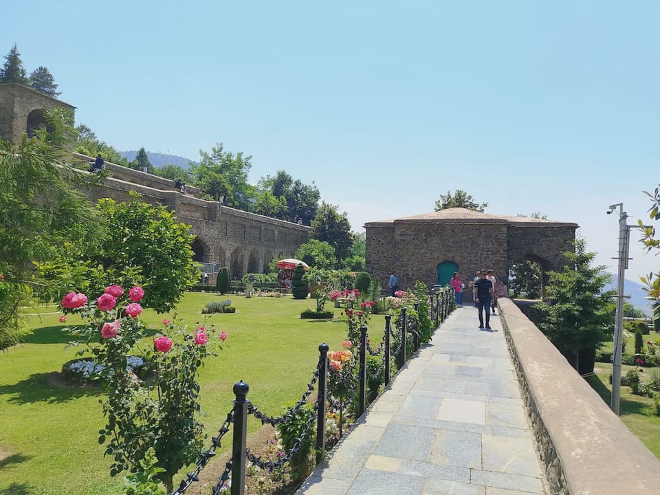 A flower-lined path beside the stone terraces at Pari Mahal.