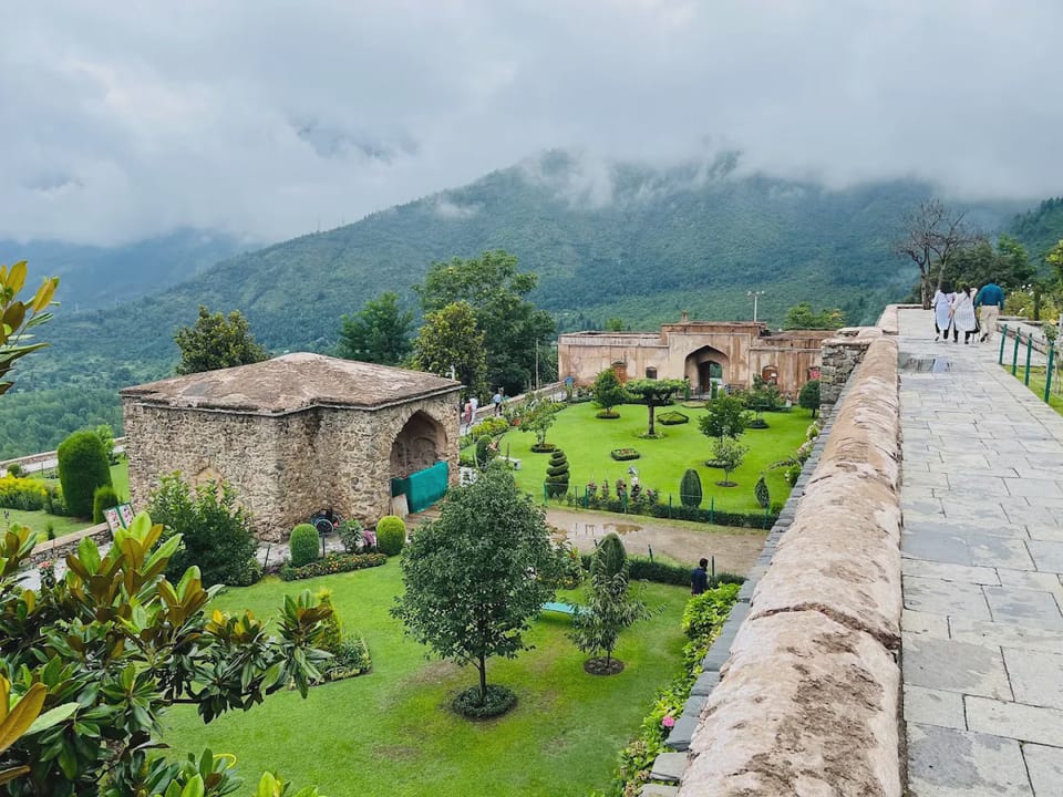 Stone walls and planted terraces at Pari Mahal beneath a cloudy sky.