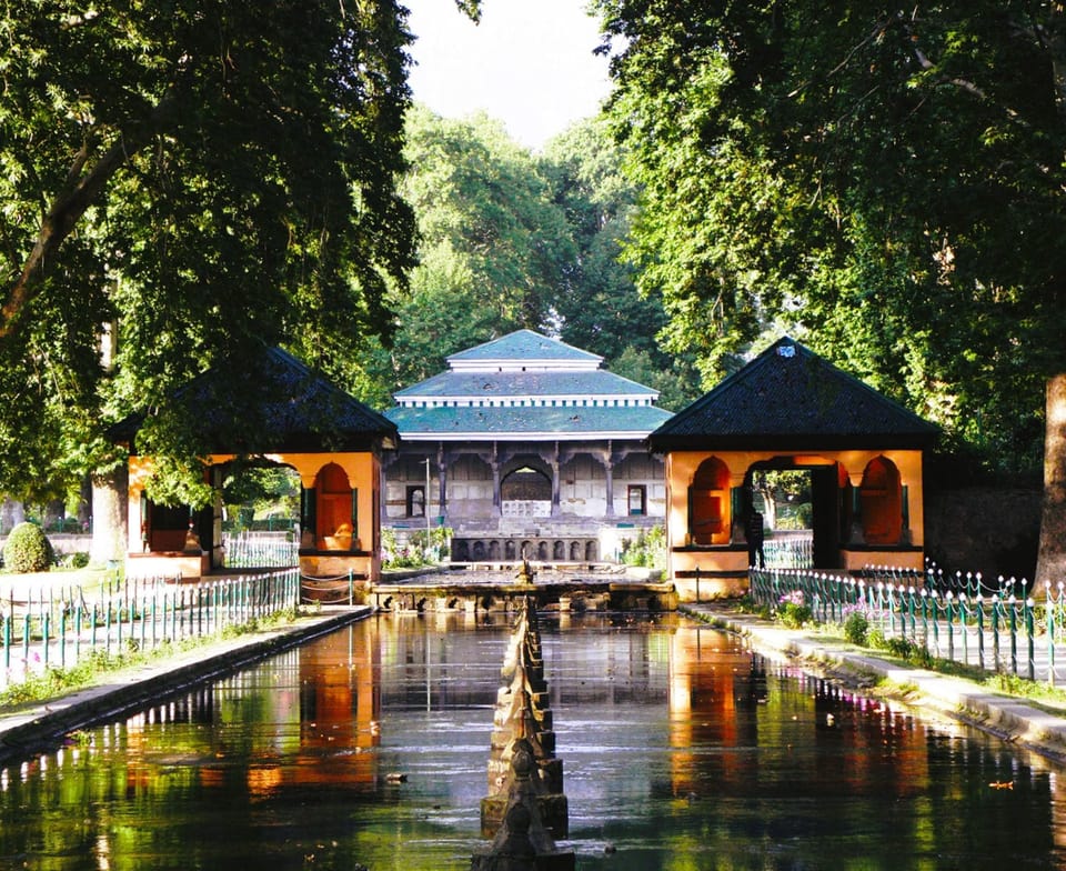 A garden pavilion and water channel shaded by trees at Shalimar Garden.